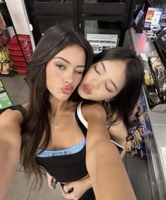 two young women are hugging each other in a grocery store, one has her tongue out