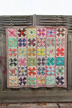 an old quilt hanging on a wooden fence