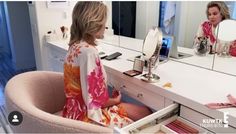 a woman sitting in a chair looking at herself in the mirror