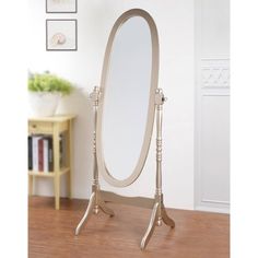 an oval mirror on stand in front of a white wall