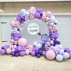 a purple and pink balloon arch with an image of a cartoon character in the middle