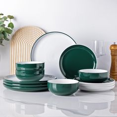 green and white dishes are stacked next to each other on a countertop in front of a plant