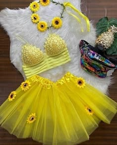 a yellow outfit with sunflowers on it and other accessories laid out next to each other