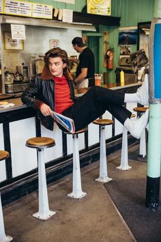 a man sitting at a bar with his feet up on the counter while reading a magazine