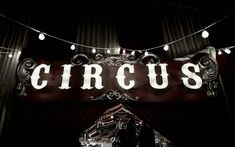 a sign that reads circus hanging from the side of a building with lights on it