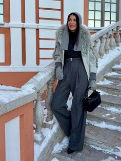 a woman standing on some steps in the snow with her hand on her hip bag