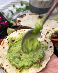 a hand holding a tortilla with guacamole on it