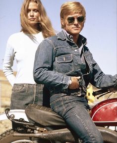 two people sitting on the back of a motorcycle