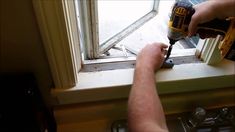 a man using a drill to fix a window