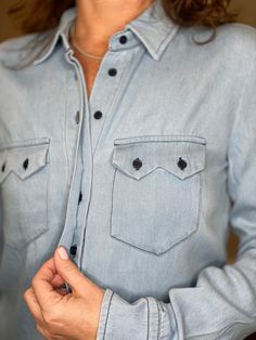 The softest, silkiest washed denim you’ll ever feel. Light, drapey and super comfortable, you will be wearing this timeless looking shirt for years to come. The Shirt reimagined for the perfect fit – powered by No Gape® button technology. Bye bye blouse gape, Hello The Shirt. Patented and designed by Rochelle Behrens to eliminate blouse gape. 100% washed cotton denim Imported Powered by our patented No Gape® button technology. The buttons are solid matte navy. Machine wash and lay flat or hang t Chic Washed Blue Tops With Pockets, Classic Medium Wash Tops For Casual Gatherings, Classic Light Wash Shirt, Classic Blue Top For Casual Gatherings, Classic Tops For Casual Gatherings, Chambray Shirt For Casual Gatherings, Everyday Button-up Tencel Tops, Everyday Washed Shirt, Everyday Tencel Button-up Tops