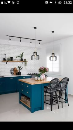 a kitchen with blue cabinets and white tile backsplash, black bar stools