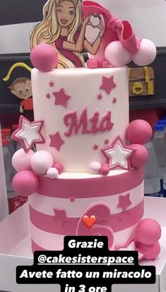 a pink and white cake with barbie on it's top is surrounded by stars