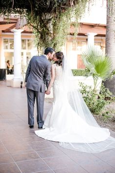 a bride and groom kissing in front of a palm tree at their wedding reception venue