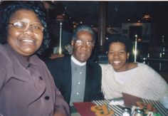 three people sitting at a table smiling for the camera