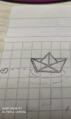 a drawing of a paper boat on top of a piece of graph paper next to a camera