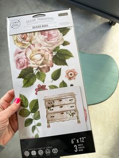 the package is being held up in front of a table with flowers and leaves on it