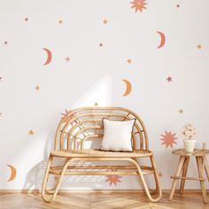 a room with stars and moon decals on the wall, next to a wicker chair