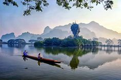 two people in a canoe on a lake with mountains in the backgrouds