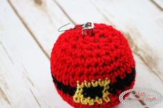 a crocheted red ball with yellow eyes and black eyeballs on it sitting on a white wooden surface