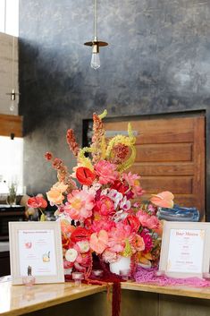 a vase filled with flowers sitting on top of a counter next to two framed pictures