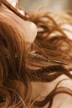 a close up of a woman with her hair blowing in the wind and eyes closed