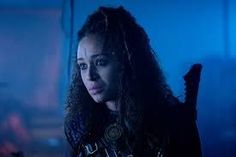 a woman with long curly hair standing in a dark room