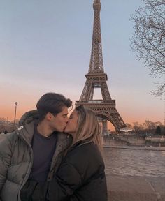 a man and woman kissing in front of the eiffel tower, paris france