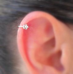 a close up of a person's ear with a single diamond on it