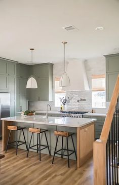 a kitchen with green cabinets and an island in the middle is seen from across the room