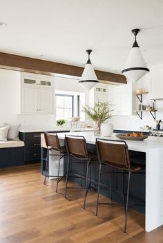 a kitchen island with four chairs and a bowl of fruit on the counter in front of it