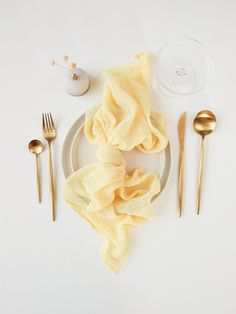 a white plate topped with yellow napkins next to silverware and utensils