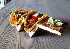 three tacos sitting on top of a wooden table