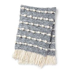 a gray and white blanket with pom poms