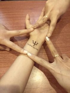 four people holding hands together with the word love written on their wrist and two fingers pointing at each other