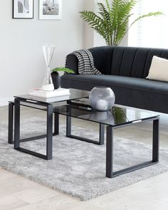 a living room with a black couch and coffee table in front of a white rug