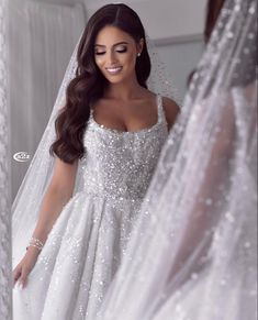 a woman in a wedding dress looking at herself in the mirror with her veil over her head