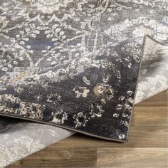 an area rug that has been placed on top of a wooden floor with a gray and white color scheme