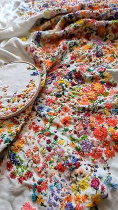 a white bed with colorful flowers on it and a wooden tray sitting on top of it