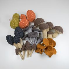 crocheted mushrooms are arranged in rows on a white surface with oranges and browns