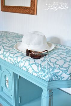 a white hat and sunglasses on top of a blue table with a mirror in the background