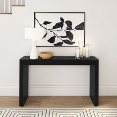 a black table with candles on it in front of a white wall and stair case