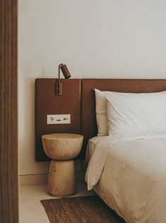 a bed with white sheets and pillows next to a night stand on the floor in a bedroom