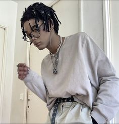 a young man with dreadlocks standing in front of a door and looking at his cell phone