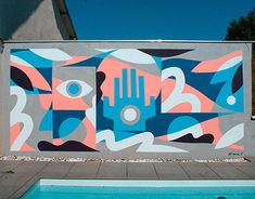 a mural on the side of a building next to a swimming pool with a blue sky in the background