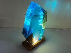 a blue crystal sculpture sitting on top of a wooden stand next to a white wall