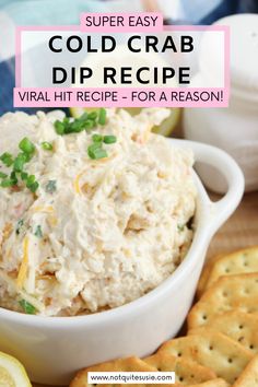 a white bowl filled with crab dip surrounded by crackers and lemon wedges