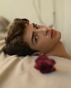 a woman laying on top of a bed next to a rose