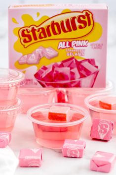 some pink gummy bears are sitting on a table next to a box of styrofoam