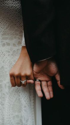 the bride and groom hold their hands together as they stand next to each other with rings on their fingers