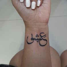 a woman's wrist tattoo with the word love written in arabic on her left hand